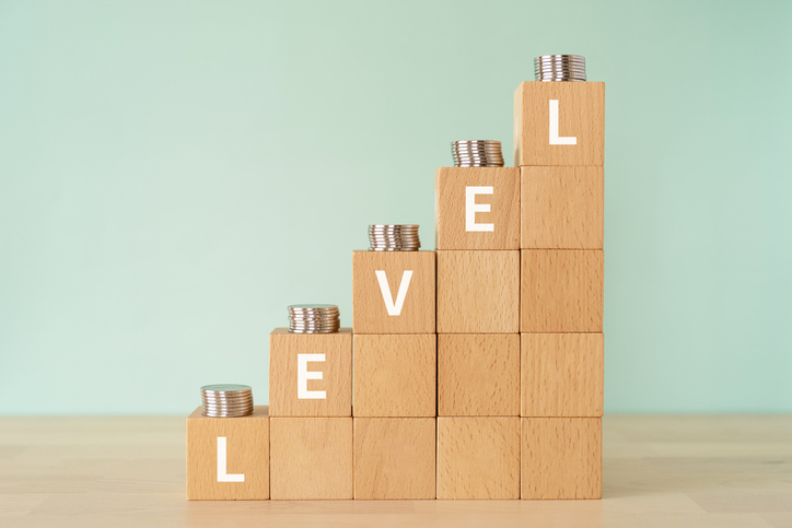 Wooden blocks with "LEVEL" text of concept and coins.